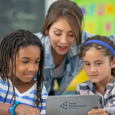 Image of a woman helping two children with a laptop